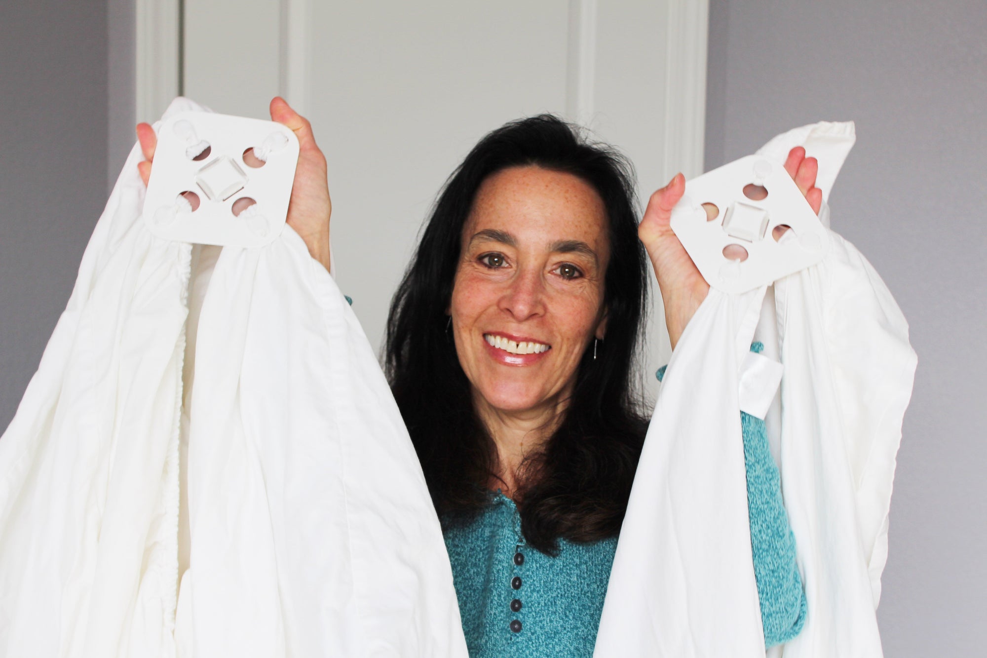 Woman holds up two white sheets attached at four points to their Wad-Frees